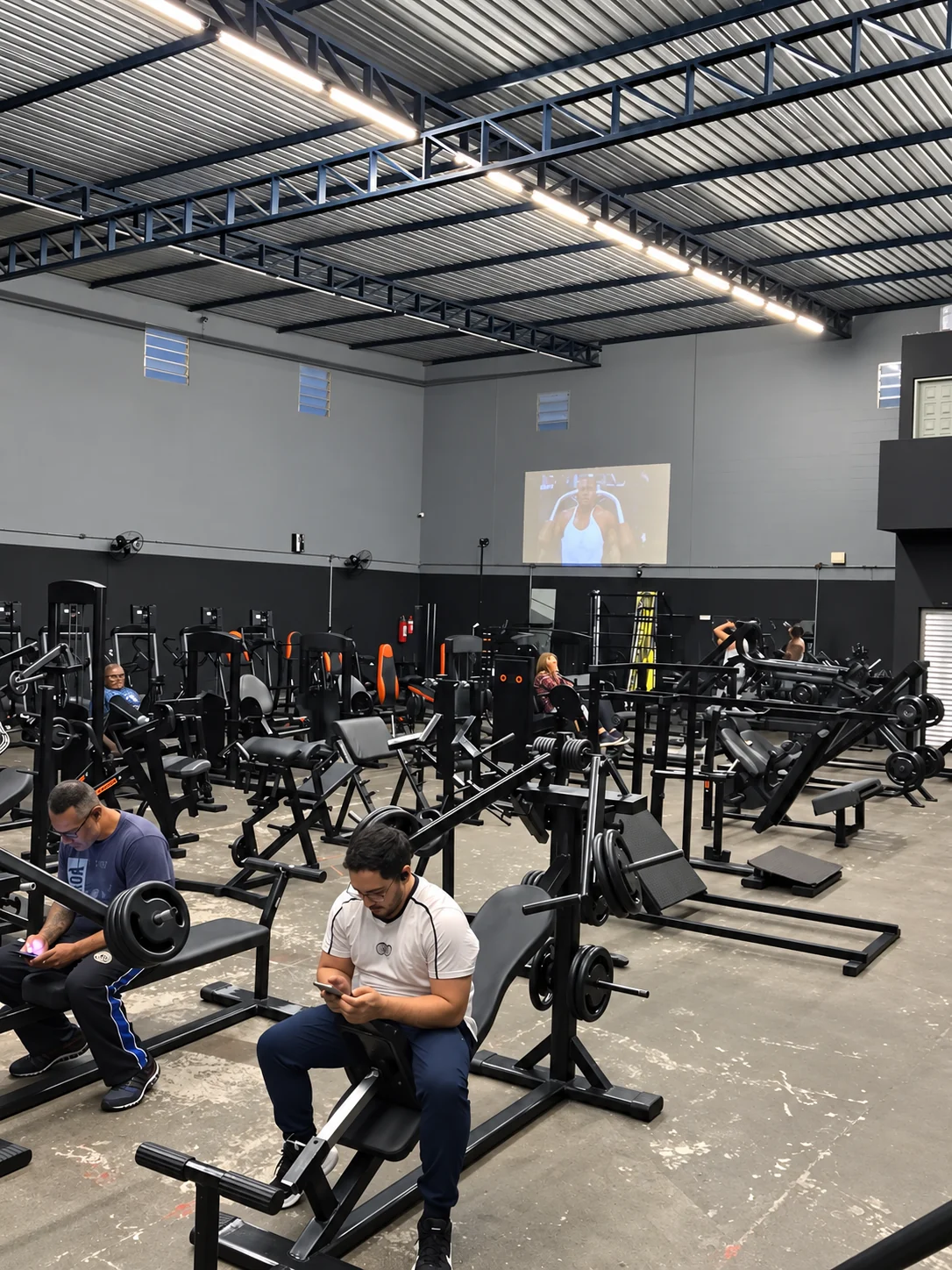 Salão de musculação com alunos e aparelhos